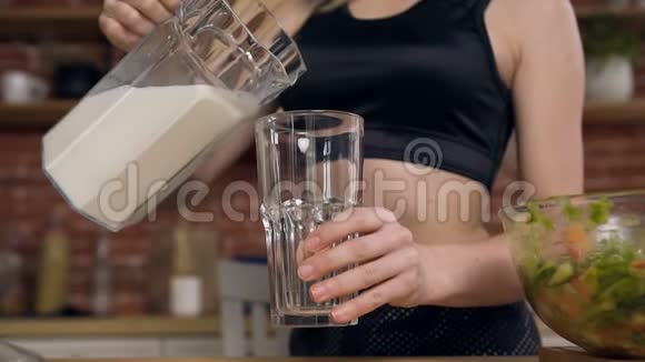 女运动员把新鲜牛奶或酸奶倒入玻璃杯中健康乳制品概念视频的预览图