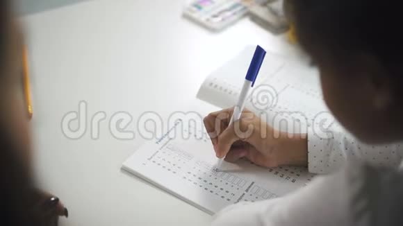 年轻的女孩坐在白色的书桌前写在笔记本上视频的预览图