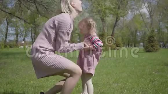 在春日可爱的年轻母亲用手把女儿纺在大自然上在公园里玩耍的女人和小孩视频的预览图