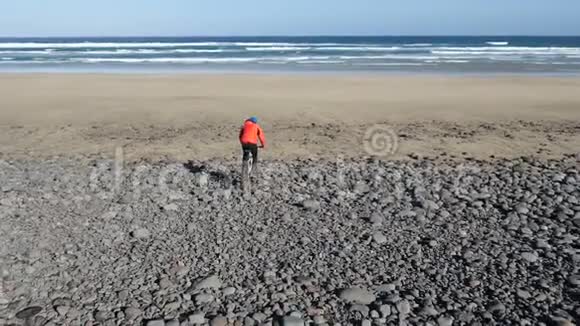 年轻人骑自行车骑在大石头上朝加那利群岛的沙滩走去兰萨罗特大西洋视频的预览图