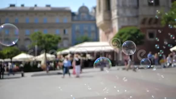 夏天在克拉科夫广场上令人兴奋的肥皂泡在人们中间低飞视频的预览图