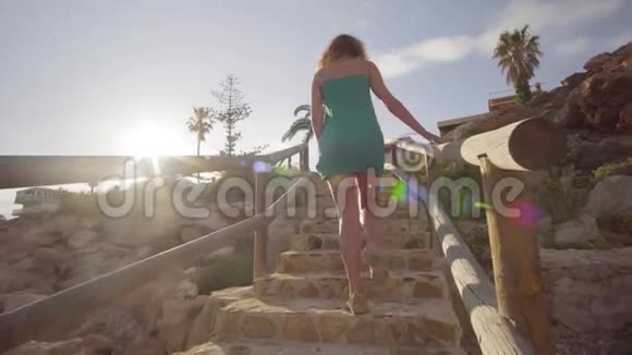 后景年轻女子从海滩上爬楼梯一个女人下午走上楼梯视频的预览图