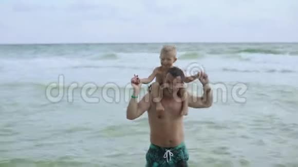 年轻的父亲和他的小儿子在海滩上玩得很开心儿子坐在爸爸肩膀上视频的预览图