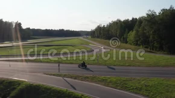骑摩托车的人开车穿过一个路口日落时间空中追踪dron射击4K视频的预览图