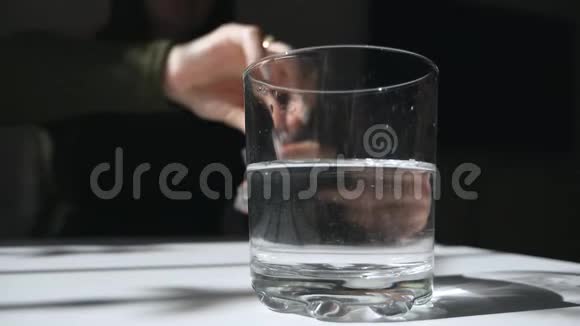 一片泡腾的止痛片落入玻璃杯中溶解阿斯匹林药片在玻璃杯里治疗视频的预览图