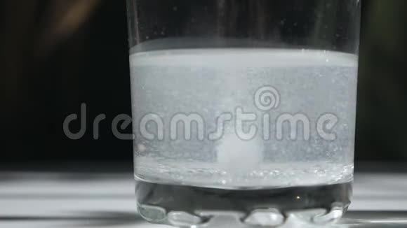 一片泡腾的止痛片落入玻璃杯中溶解阿斯匹林药片在玻璃杯里治疗视频的预览图