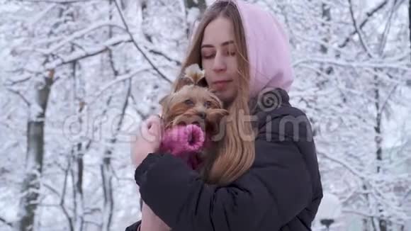 肖像可爱的少女长发披着兜帽抱着一只穿着羊毛衫的约克郡猎犬视频的预览图
