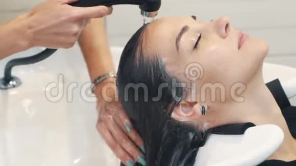 在美容店里美发师向女性近距离洗头动作缓慢视频的预览图