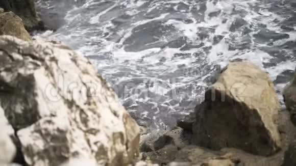 海中的岩石上有泡沫破裂的灰色波浪行动从岩石向大海望去视频的预览图