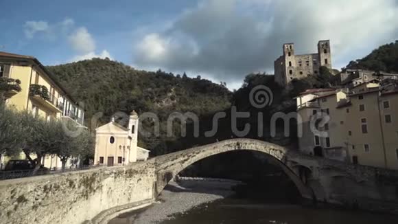 在干涸的河道上方的老桥的近景背景是老建筑和被覆盖的山脉视频的预览图