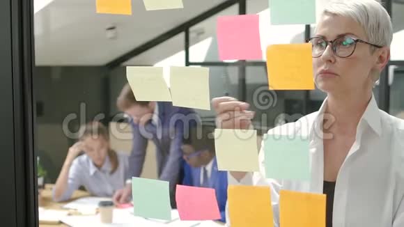 女商人看着黏糊糊的纸条在办公室会议室里深思视频的预览图
