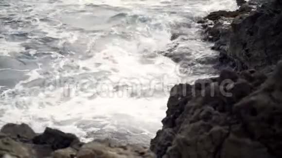 海浪围绕着岩石海洋海岸战斗行动看汹涌的海浪冲击着岩石视频的预览图