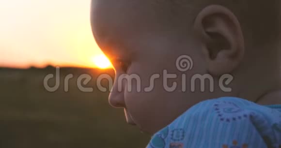 可爱的宝贝在夏天的日落时在慢动作中快乐地看着妈妈视频的预览图