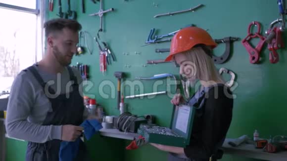 在汽车服务站实习专业机械师教年轻女孩戴上头盔并配备一套工作工具视频的预览图