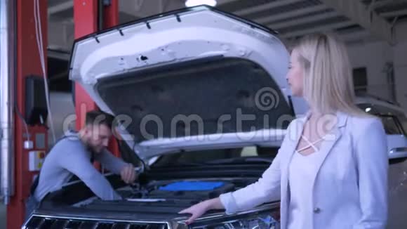 汽车修理工作过程中女客户车主的肖像技师用敞篷汽车修理视频的预览图