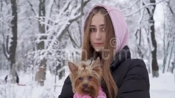 一位留着长发的孤独少女抱着一只穿着羊毛衫的约克郡猎犬双手抱着狗视频的预览图
