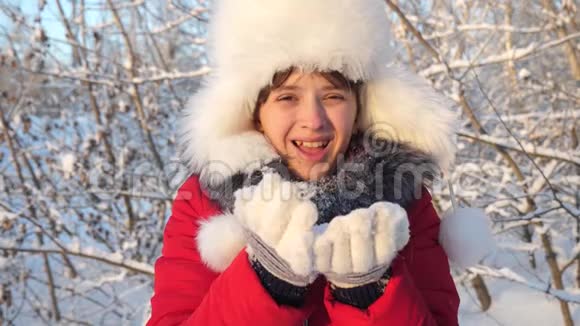 快乐的少女在日落时吹雪花在冬天的公园里微笑慢动作小女孩吹雪花视频的预览图