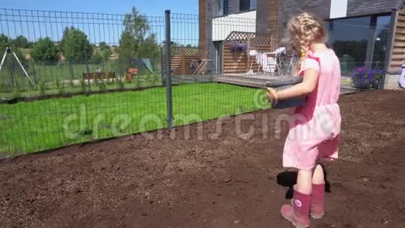 小女孩在联排别墅院子里种新的草坪种子万向节运动视频的预览图