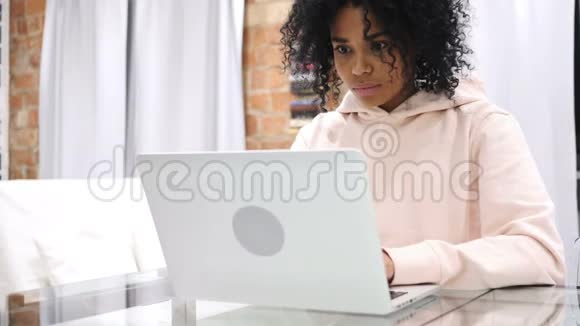 兴奋的非裔美国妇女在坐在沙发上的笔记本电脑上庆祝成功视频的预览图
