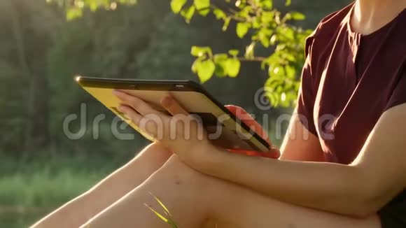 一个年轻女子的手坐在公园的绿草上在石碑上工作教育学生商业视频的预览图