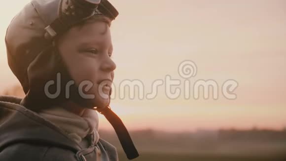 特写镜头小快乐男孩穿着老飞行员服装戴着老式航空眼镜在日落场慢动作视频的预览图