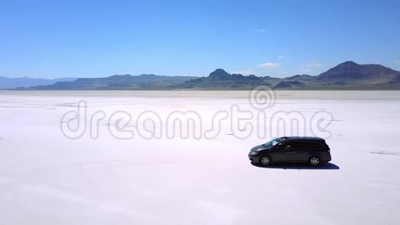 空中无人驾驶飞机拍摄的银色小型货车行驶在大气中的邦尼维尔盐湖沙漠公寓视频的预览图