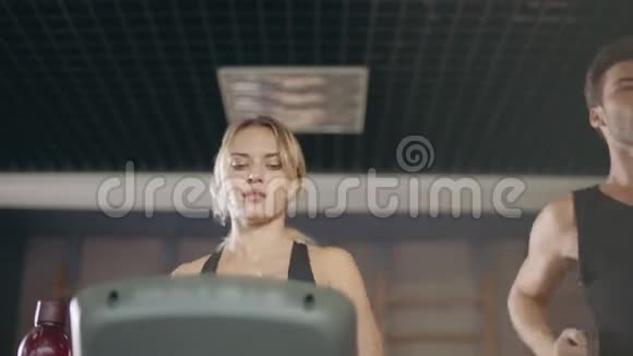 在健身房的跑步机上一对情侣一起跑步视频的预览图