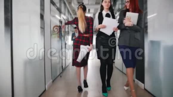 一位情绪激动的商界女性在办公室走廊上与同事跳舞同事们转过身来视频的预览图