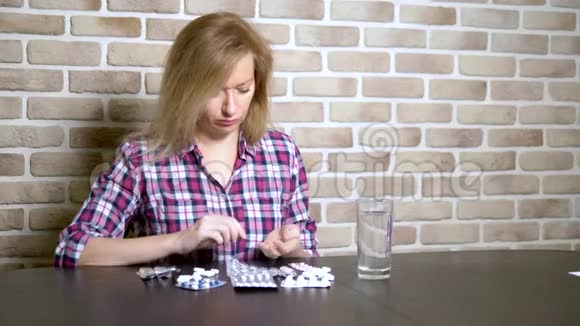 生病的悲伤的女人坐在桌边整理药片保健和维生素缺乏的概念视频的预览图