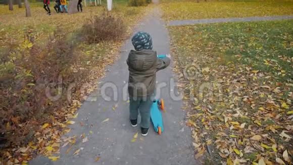 小男孩在城市公园里学骑滑板车主动休闲和儿童户外运动视频的预览图