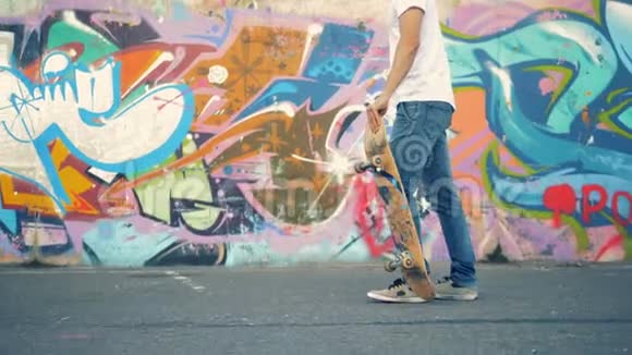 年轻人跳上滑板开始沿着涂鸦墙骑行视频的预览图