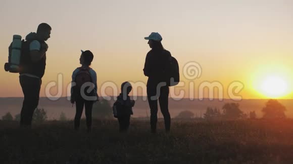 日落时父母和两个孩子在山上散步剪影幸福美丽的家庭视频的预览图