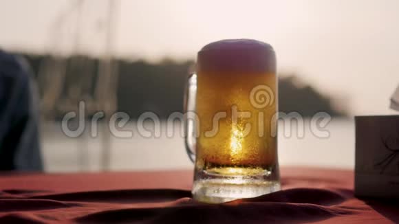 背景中带有夕阳的啤酒杯一个日落时分啤酒从瓶子里倒入杯子视频的预览图