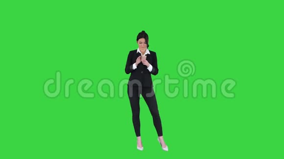 年轻的商务女性听着电话里的音乐在绿色屏幕上跳舞Chroma键视频的预览图