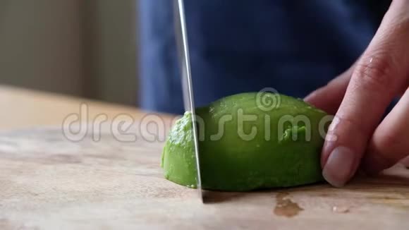 一位中年厨师用木板上的刀切牛油果特别靠近视频的预览图