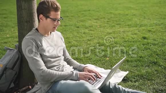 年轻可爱的戴着黑眼镜的家伙用电脑浏览阅读和打字视频的预览图