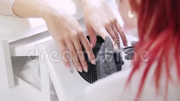 美容店里戴着手套的美甲女士在涂胶前用指甲锉钉给客户指甲视频的预览图