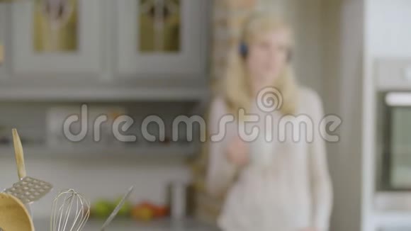 厨房里的女人用耳机听音乐喝咖啡视频的预览图