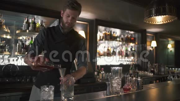 大胡子的酒保把朗姆酒倒在金属罐里然后倒在玻璃里现代酒吧里有很多酒吧的酒吧老板视频的预览图