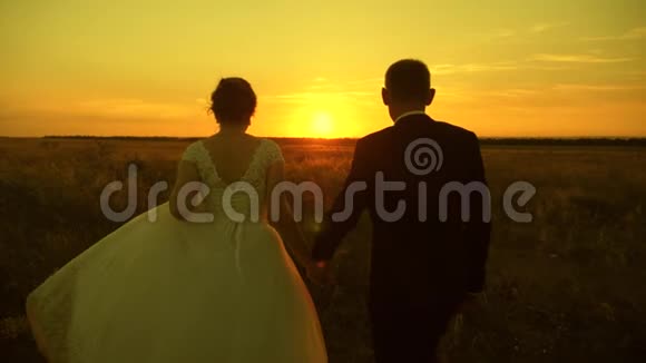 在蜜月旅行中恋爱的情侣新郎新娘慢动作快乐的男人和女人在日落时跑步视频的预览图
