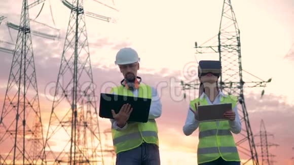 两名专家正在操作他们的计算机同时站在电力线附近工业使用中的虚拟现实视频的预览图