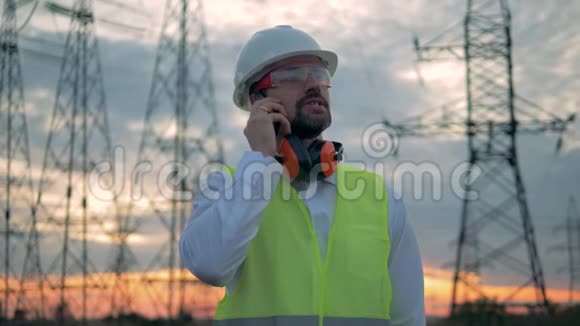 电力线路和一名男性专家整理电话视频的预览图