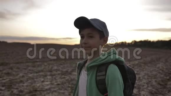 带背包的有趣男孩在户外日落时散步旅行理念视频的预览图