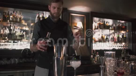 酒保把酒精倒在烧杯里然后用倒入玻璃中展示了他的技能现代酒吧的酒吧服务员视频的预览图
