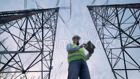 两个高大的电塔和一个男检查员在它们之间工作视频的预览图