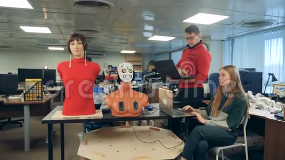 男人和女人控制机器人使用笔记本电脑关闭视频的预览图