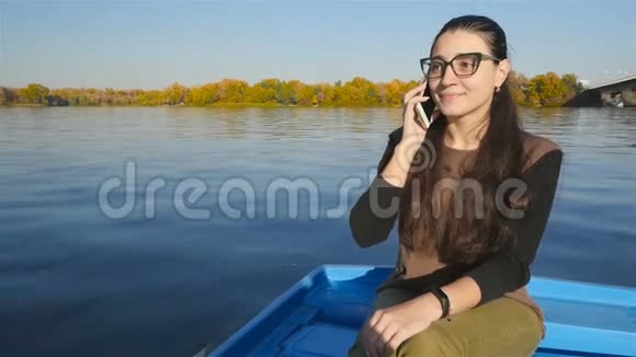那个女孩坐在水上的船上打电话很漂亮的笑容晴天慢动作视频的预览图