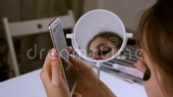 家里的女孩监测眼睛周围的皮肤化妆品护理韩国化妆品女孩用电话视频的预览图