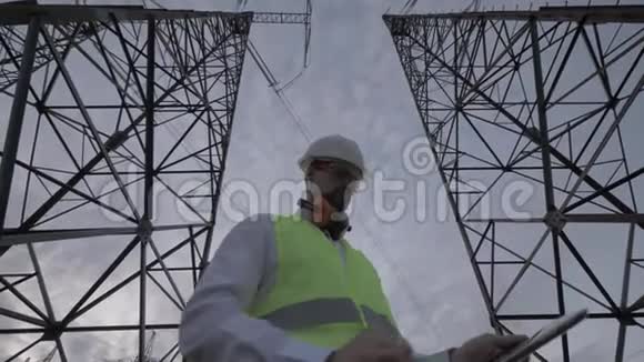 乌云密布的天空和一个男技术员在高大的ETL塔之间工作视频的预览图