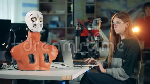 科学家机器人与笔记本电脑一起工作控制机器人工程师与未来派人形机器人半机器人视频的预览图
